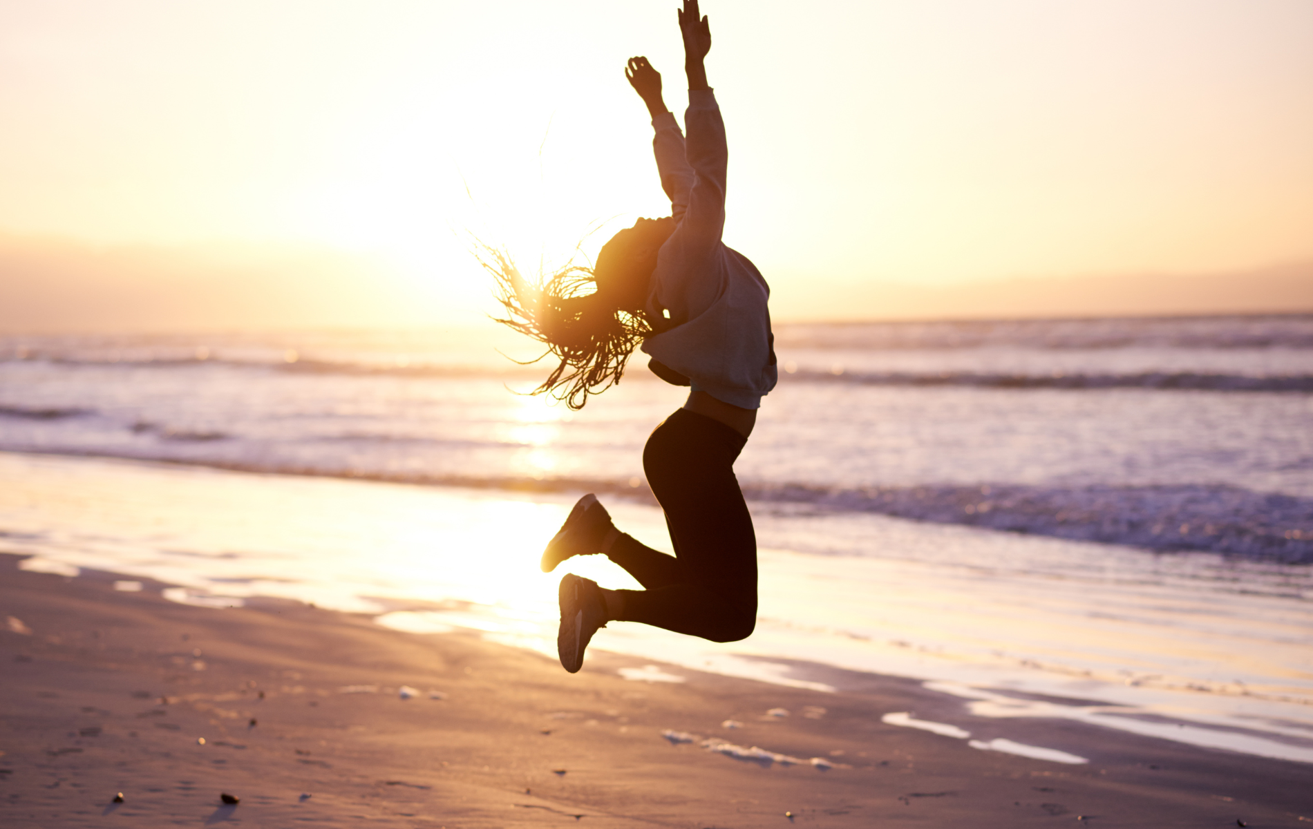 une femme à la plage en plein saut