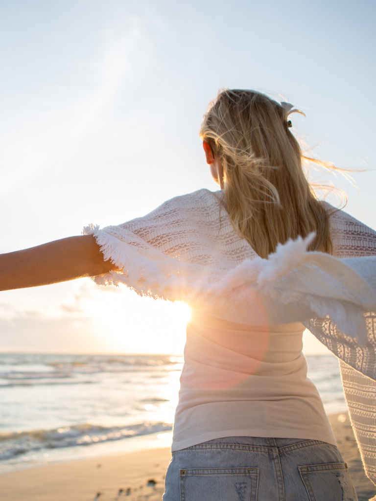 femme face à la mer qui a les bras tendus