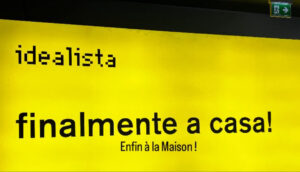 Affiche italienne jaune avec le texte Finalmente a casa – Enfin à la maison, symbole de la nationalité originelle de l’âme et du retour à sa Terre d’âme en Italie